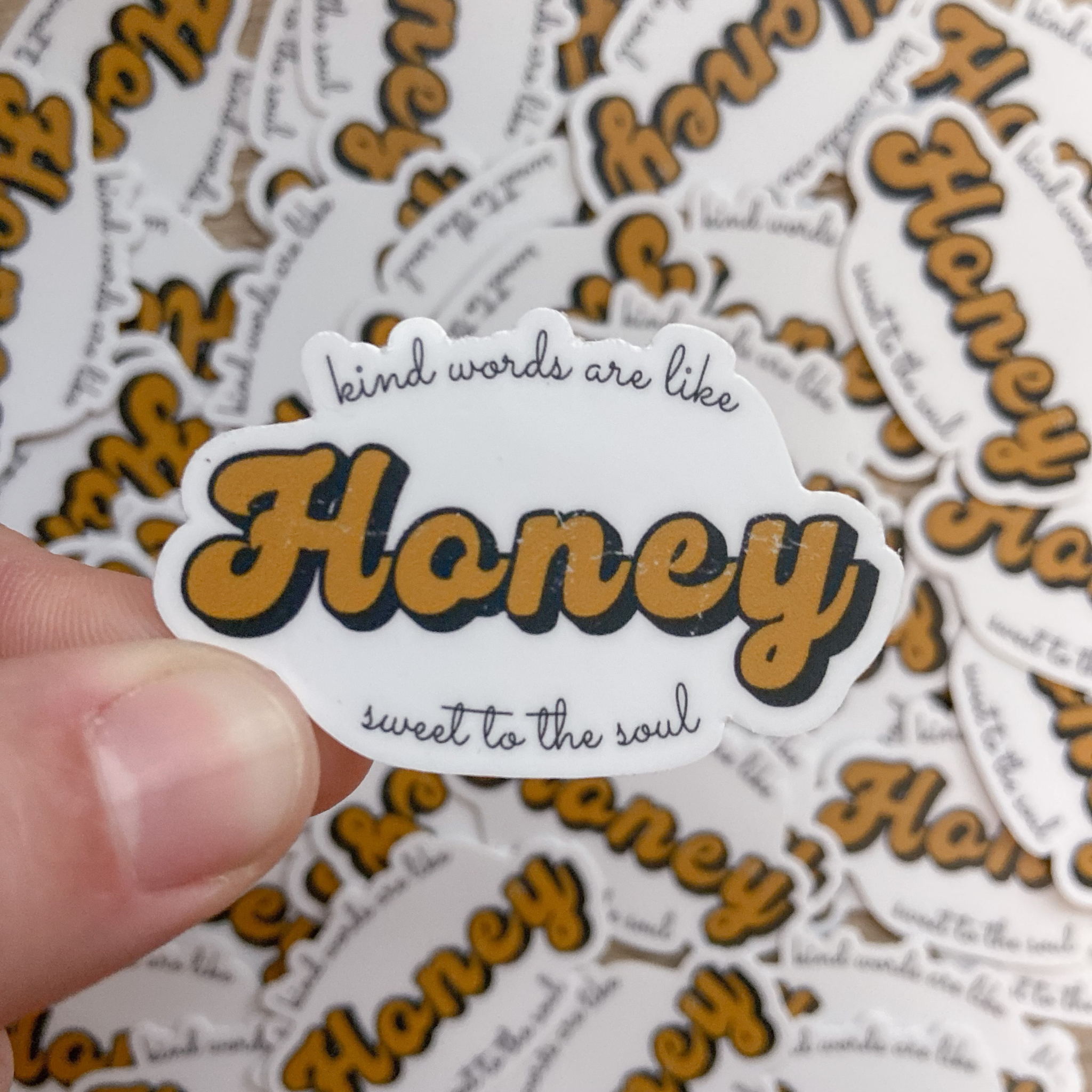 The words "kind words are like honey sweet to the soul" on a white sticker