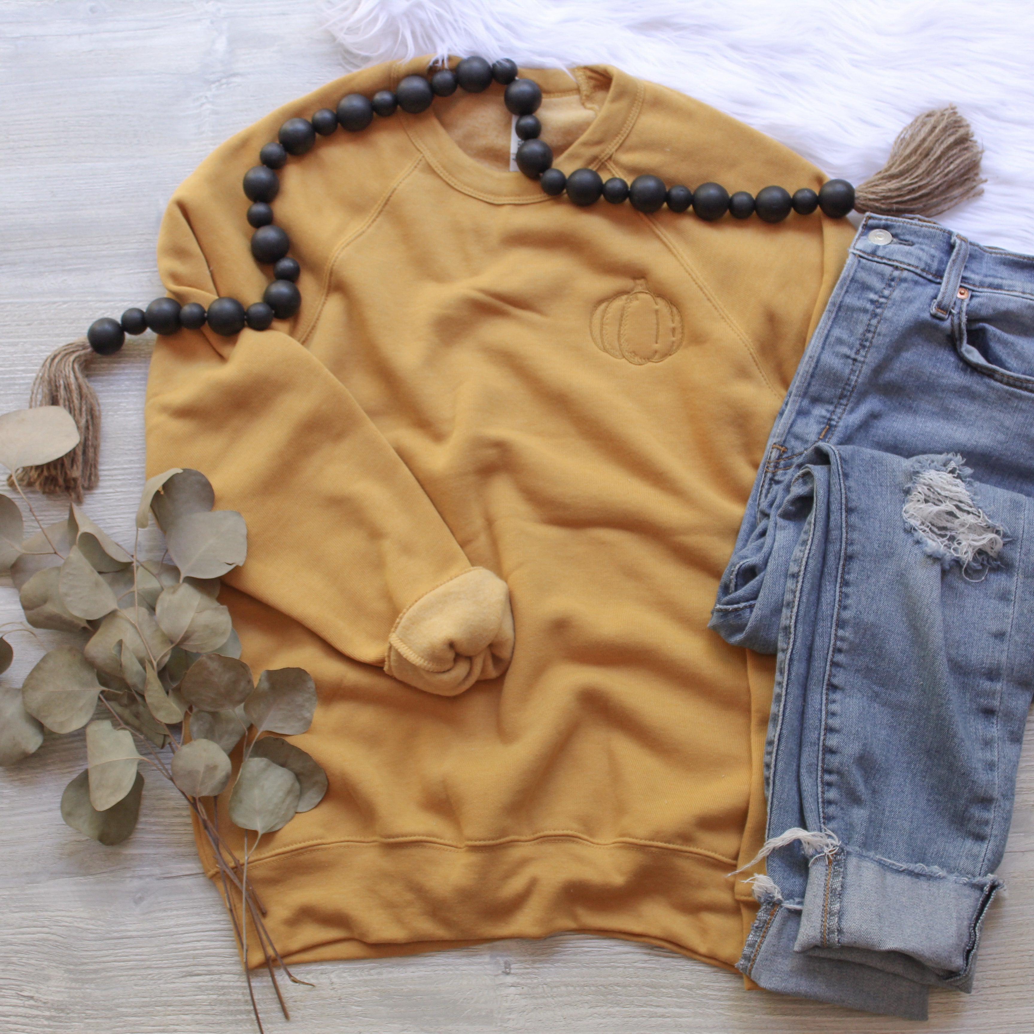 Mustard gold crewneck that has a small pumpkin embroidered on it