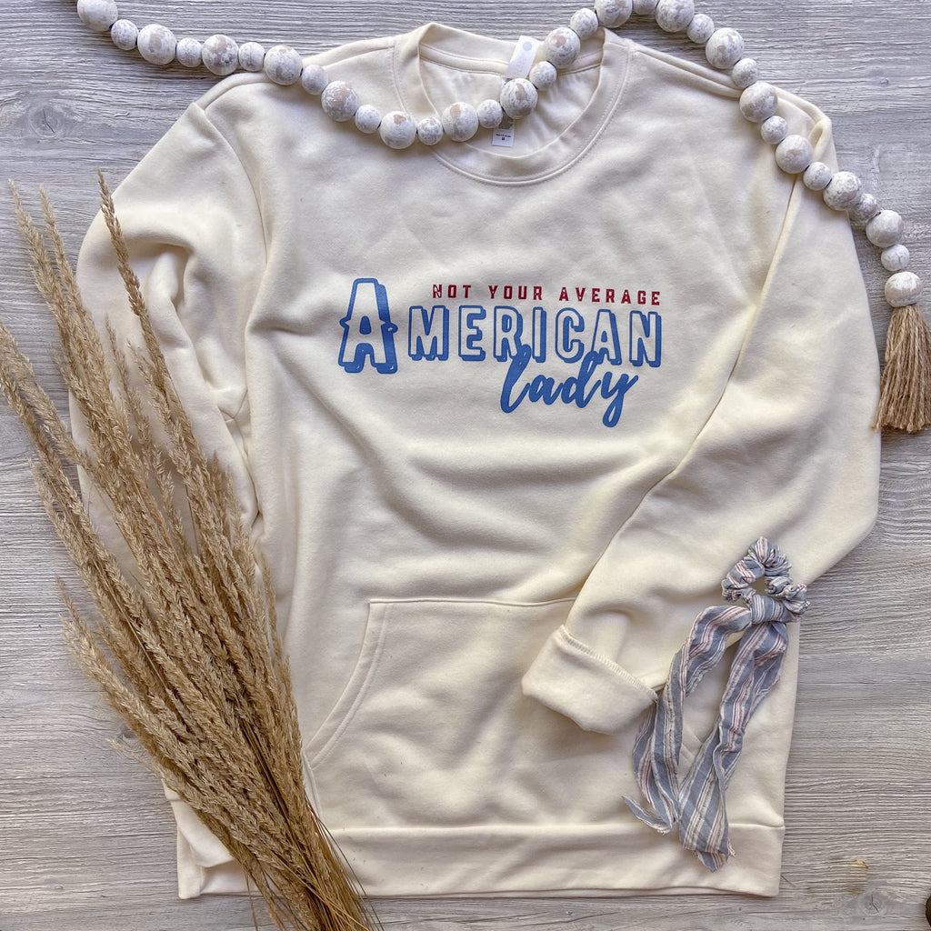 Cream crewneck with pocket that says not your average american lady on it in red white and blue